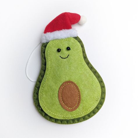 "This Avocado Christmas ornament is going to look extra charming on your Christmas tree.  Handmade out of felt and stitched and stuffed for a bit of dimension, eyes are hand sewn on with a cute little fluffy pom pom santa hat.  Comes with its own hanger in minimal waste packaging.  Measures approx. 6.5\" high by 4\" wide, 1/2 an inch thick. (See hand for scale.)  NOTE: These are handmade, so slight variations in the facial features are to be expected.  Each one has received quality stamp of appr Pom Pom Santa, Felt Avocado, Avocado Christmas, Christmas Tree Handmade, Crafty Hobbies, Felt Crafts Christmas, Tree Handmade, Felt Embroidery, Felt Christmas Tree