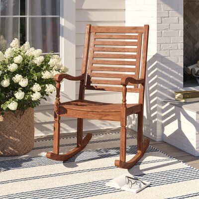 Three Posts™ Rock as you read or relax under the sun with this classic rocking chair, perfect for petite patios and big backyards alike. Crafted from solid acacia wood, this piece sport a neutral wood grain finish that helps ward off wear from weather, water, and UV. Slats across the back and seat highlight this design’s clean lines, while turned accents prop up the armrests for a traditional touch. We recommend you apply teak oil as needed to maintain this chair’s finish. Assembly is required. Front Porch Rockers, Classic Rocking Chair, Teak Rocking Chair, Solid Wood Chairs, Studio Color, Patio Rocking Chairs, Rocker Chairs, Teak Oil, Wood Patio