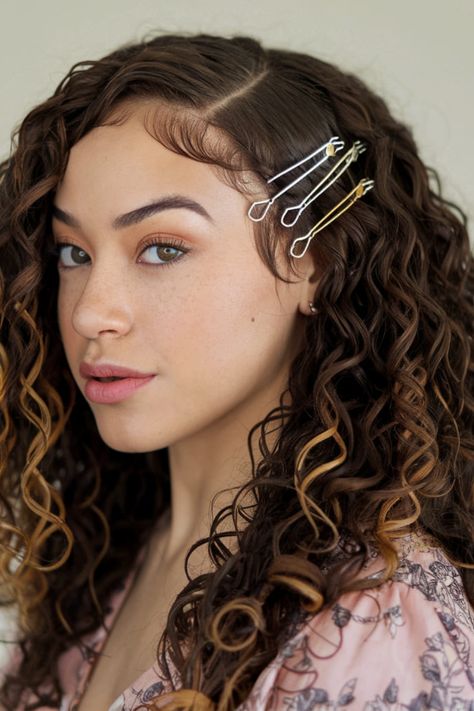 For a unique twist, use decorative bobby pins to create a design on one side of your curls. This accessory adds a touch of creativity to your long layered hair while keeping it sleek and stylish. Hair With Accessories, Decorative Bobby Pins, Long Layered Hairstyles, Long Layered Curly Hair, Half Up Curls, Curly Layers, Messy Curly Bun, Layered Curls, Side Swept Curls