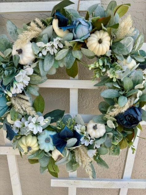 If you're looking for a blue fall pumpkin wreath with a coastal vibe, here it is!  We capture so many different textures to make the most eye pleasing wreath!!  A natural grapevine wreath base is embellished with soft lambs ear and eucalyptus greenery, and topped with peonies in different shades of blue, delicate white cherry blossoms and eucalyptus leaves in the richest shade of blue.  Top it off with blue and cream pumpkins and pampas grass!  There is so much dimension in this wreath, making it a showstopper for your front door, or the perfect addition to the wall above your fireplace mantel or a beautiful mirror in your home.  Only 1 Available! 22 inch diameter For indoor or covered outdoor use Lifelike greenery with artificial and natural embellishments Blue Eucalyptus Wreath, Blue Halloween Decorations, Fall Decor With Blue Accents, Fall Decor With Blue, Thanksgiving Front Door, Holidays Decorations, Coastal Fall, Fall Wreath For Front Door, Pumpkin Arrangements