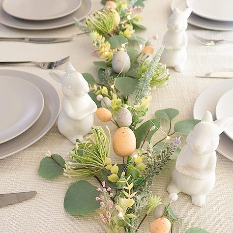 The photo shows an image of a plain white table cloth set with grey stacked plates and cutlery. It is decorated with an Easter themed garland made of faux eucalyptus and delicate spring flowers in pink and yellow. Small pastel coloured Easter eggs are also delicately placed along the garland. There are porcelain white rabbit decorations places alongside the finished table scape. Teen Easter Basket, Adult Easter Baskets, Easter Egg Garland, Baby Easter Basket, Easter Egg Fillers, Eggs For Sale, Easter Baskets For Toddlers, Pumpkin Garland, Easter Garland