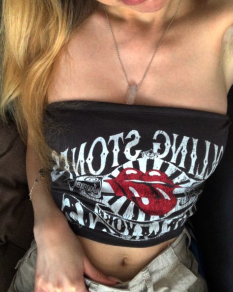 A girls body visible, mainly the upper part. Shes wearing a strapless top with the Rolling Stones logo. Its brown. Shes wearing a pink quartz necklace and light beige cargo pants. Brown Tube Top Outfit, Band Tshirt Aesthetic, Band Tee Outfits, Tshirt Aesthetic, Beige Cargo Pants, Tube Top Outfits, Rolling Stones Band, Strapless Shirt, Beige Cargo