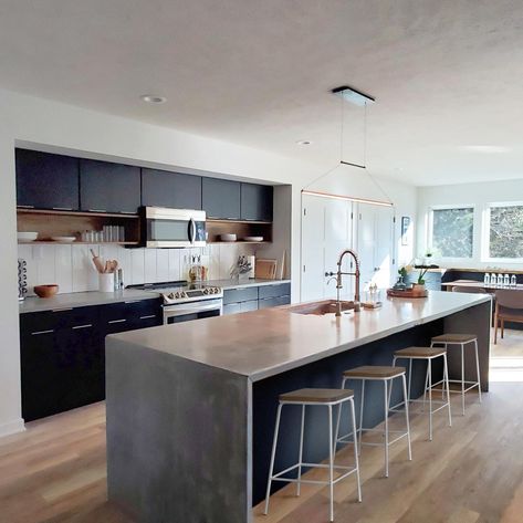 Waterfall Island Kitchen Concrete, Long Countertop Kitchen, Black Kitchen With Concrete Counter, Black Kitchen Cabinets Concrete Counter, Black Kitchen Concrete Counter, Gray Waterfall Island, Polished Concrete Island Kitchen, Concrete Waterfall Island, Waterfall Island Kitchen Modern