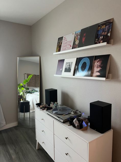 Corner of bedroom with grey floors. Record player on white dresser. Records displayed on wall on while ikea shelves. Gold frame mirror in corner with plant in black plant stand. Wall Decor Bedroom Men Room Ideas, Street Style Bedroom, Tv In Room, Street Style Room, Mens Room Decor, Mens Bedroom Decor, Vinyl Room, Chill Room, Apartment Living Room Design