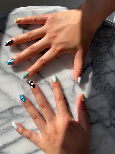 An overhead view of the nails on each hand, each with a different design. From thumb to pinky: a yellow smiley face, a white and green yin & yang symbol, black-and-white checkers, blue sky with white clouds, and a light blue background with a yellow flower in the center.

On the right hand, thumb to pinky: light blue sky with white clouds, green abstract design, blue and white checkers, black and white yin & yang sign, yellow   smiley face Best Nail Art Designs, Professional Nails, Cool Nail Art, Nail Artist, Fun Nails, Summer Nails, Nail Art Designs, Art Design, Nail Art