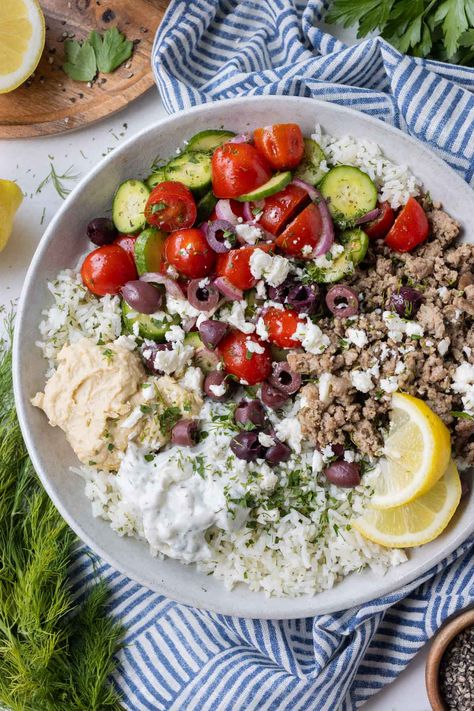 These Greek Ground Turkey Rice Bowls are bursting with fresh Mediterranean flavor from a homemade Greek seasoning mix—the secret to why the ground turkey tastes so incredible! Paired with bright lemon and herb rice, a cucumber tomato salad, and a duo of tzatziki sauce and hummus, they are one of our go-to meal prep options on busy weeknights—even picky eaters give this one two thumbs up! Greek Hummus Bowl, Ground Turkey Tzatziki Bowls, Greek Ground Chicken Bowls, Greek Bowls Ground Turkey, Ground Turkey Recipes For Dinner Mediterranean, Greek Turkey Rice Bowl, Mediterranean Diet Recipes With Ground Turkey, Ground Turkey Mediterranean Bowl, Turkey Greek Bowl