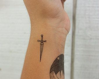 Small Meaningful Symbol Tattoos, Small Dagger Tattoo Simple, Tiny Dagger Tattoo, Dagger Finger Tattoo, Tattoo Under Ear, Small Dagger Tattoo, Snake And Dagger Tattoo, Meaningful Symbol Tattoos, Taboo Tattoo