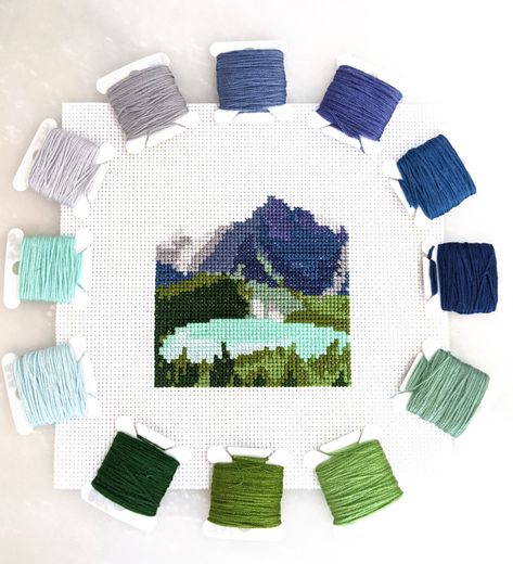 "You'll love stitching this beautiful Glacier National Park mini cross stitch landscape - a view from the Grinnell Glacier Trail! This pattern captures the incredible mountains, forests, and brilliant blue water found in Glacier, all in the very accessible 50x50 stitch (3.5 inch) size (or about 5\" tall with optional text). PDF download includes: - preview of finished piece - full color pattern with symbols - black and white pattern with symbols - DMC thread list with color names and numbers - a Cross Stitch Landscape, Park Landscape, Small Cross Stitch, Mini Cross Stitch, Mini Cross, Small Crosses, Glacier National, Glacier National Park, Cross Stitch Art