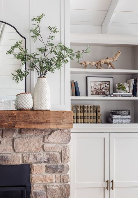 stone fireplace with rustic mantel with white vase filled with faux branches Stone Fireplace With Limestone Mantel, Fireplace Mantel Styling, Stone Fireplace No Mantle, Driftwood Fireplace Mantle, Stone Mantel Fireplace, Stone Fireplace Mantel Decor, Stone Fireplace Mantel Decorating Ideas, Stone Fireplace With Bookshelves, Stacked Stone Fireplace With Mantel