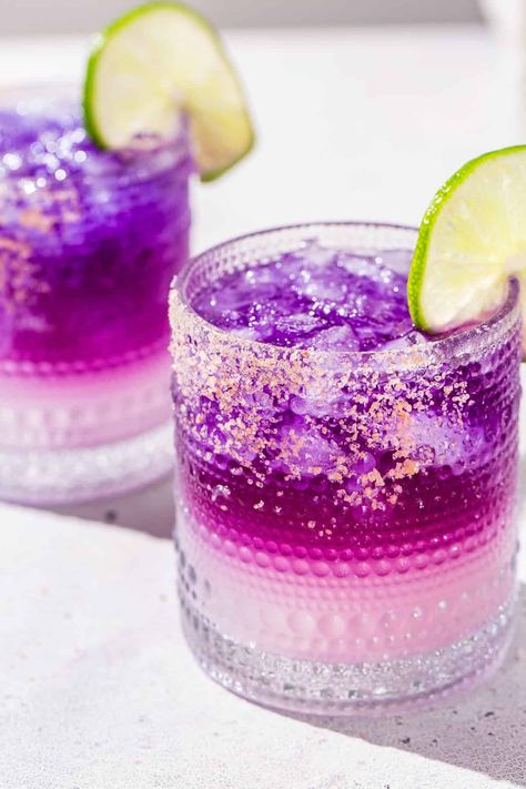 The Galaxy Margarita is as tasty as it is beautiful! Tequila that's naturally colored by butterfly pea flowers is layered on top of a Cointreau and lime base. Edible glitter takes it to the next level! It is a fun galactic spin on a classic margarita. This is the perfect margarita recipe for a girls night, bachelorette or just a night of stargazing! Purple Margarita, Margarita Flight, Perfect Margarita Recipe, Tequila Drinks Recipes, The Perfect Margarita, Butterfly Pea Flowers, Perfect Margarita, Tacos And Tequila, Disco Theme