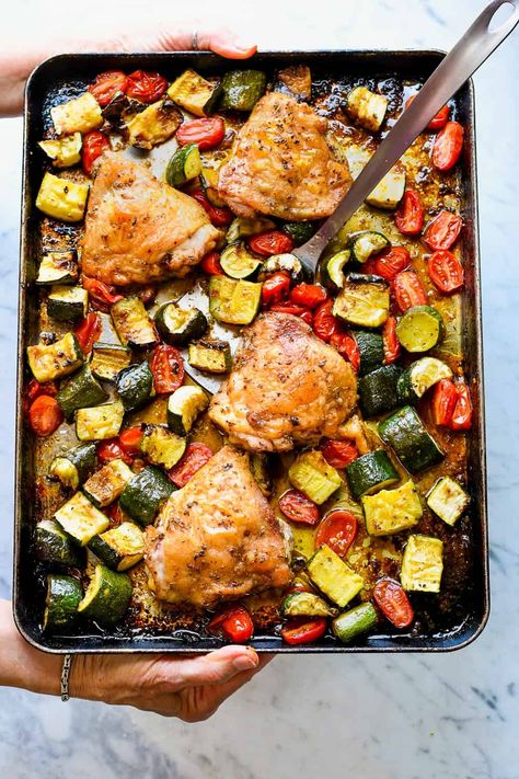 In this delicious summery sheet pan dinner chicken thighs are seasoned with garlic and herbs and roasted with tender chunks of zucchini and cherry tomatoes that caramelize as they cook. The fresh basil sprinkled on just before serving enhances the summer tastes. This meal is gluten free, paleo and incredibly simple. Chicken Thigh Veggie Bake, Sheet Pan Chicken And Zucchini, Chicken Thighs And Zucchini Recipes, Sheet Pan Chicken Thighs And Veggies, Chicken Thigh Sheet Pan Dinner, Dinner Chicken Thighs, Zucchini And Potatoes, Chicken With Zucchini, Chicken And Zucchini