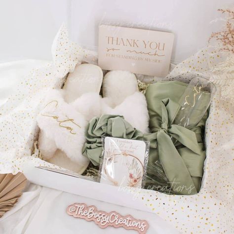 Step into a world of luxury with our Sage Green Fluffy Slippers Bridesmaid Gift Box. Designed for the modern bride who wants to spoil her bridal party, this exquisite gift box includes a sumptuous satin robe, a matching hair scrunchie, a personalized mimosa champagne glass, and a pair of white personalized fluffy slippers together with a minimal knot bracelet. Indulge your bridesmaids in pure comfort and style as they prepare for your special day. These handmade slippers are not only cozy and so Gift For Bridesmaids On Wedding Day, Bridesmaid Morning Of Wedding Gift, Morning Of Bridesmaid Gifts, Day Of Bridesmaid Gifts Mornings, Sage Green Bridesmaid Gifts, Day Of Gifts For Bridesmaids, Thank You Bridesmaid Gifts, Bridesmaid Gifts Wedding Day, Bridesmaid Proposal Green