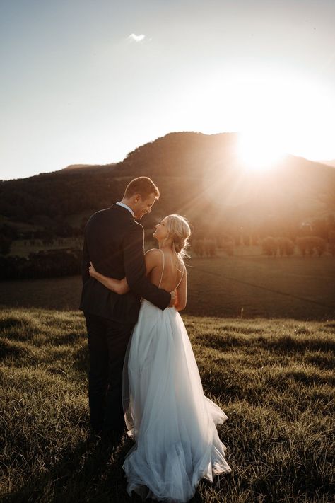 Couple looking at each other with the sun setting behind the mountains in front of them. If you want to plan your wedding for sunset, check out this guide!