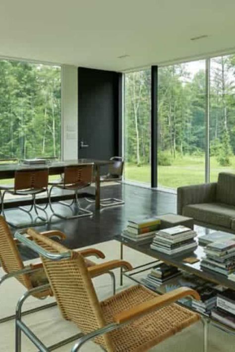 The living room and dining area make sup this large open layout great room surrounded by glass walls. The living room area has a gray sofa paired with a glass-top coffee table and a couple of armchairs. #GreatRoomIdea #GlassWallLivingRooms Courtesy of Toptenrealestatedeals.com. Office With Sofa Layout, Decorating High Ceilings, For Ceiling Ideas, Tv Lighting Ideas, Office With Sofa, Home Office With Sofa, Big Windows Living Room, Modern Kitchen And Dining, Dining Room Arrangement