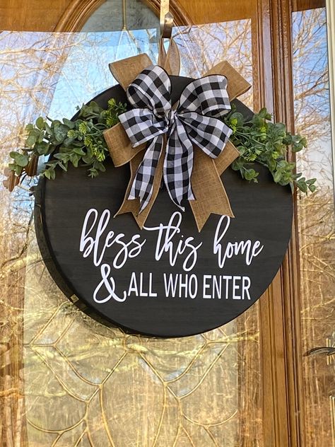 "Black stained Round wooden round door hanger with white Bless This Home And All Who Enter, black and white buffalo plaid and beige bow accented with greenery and a beige/neutral hanger Material: Black Stained Wooden Round Board Black and White Buffalo Plaid and Beige Ribbon Beige Wall Hanger Glue Staples Faux Greenery *greenery may vary depending on availability* Word: Bless This Home And All Who Enter in white vinyl Size: Approximately 18\" in diameter Approximately 1\" thick Thank you for che Custom Hangers, Wood Door Hanger, Custom Wood Doors, Circle Crafts, Door Hangers Diy, Wooden Signs Diy, Door Signs Diy, Wood Wreath, Wooden Door Signs