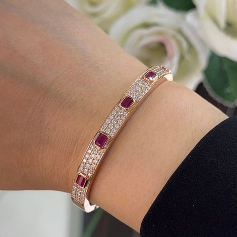 This bangle bracelet is a stunning testament to elegance and sophistication, crafted from lustrous 18 karat rose gold to exude warmth and charm. Adorning the bracelet are a mesmerizing array of natural diamonds and radiant emerald-cut rubies, creating a captivating contrast of sparkle and color. The bracelet features round-cut diamonds totaling 1.63 carats, boasting a remarkable G color and VS2 clarity. Set in a combination of pave and bezel settings, the diamonds shimmer with brilliance and fire, adding a touch of glamour to the design. Interspersed among the diamonds are enchanting emerald-cut rubies totaling 1.42 carats, set in bezel settings to accentuate their vibrant red hue. Their exquisite beauty adds a rich and captivating dimension to the bracelet, creating a striking harmony wit Ruby Bangles, Diamond Bangles, Diamond Bracelet Design, Ruby Bracelet, Diamond Bangles Bracelet, Bangles Jewelry Designs, Gold Jewelry Indian, Diamond Bangle, Bangles Jewelry