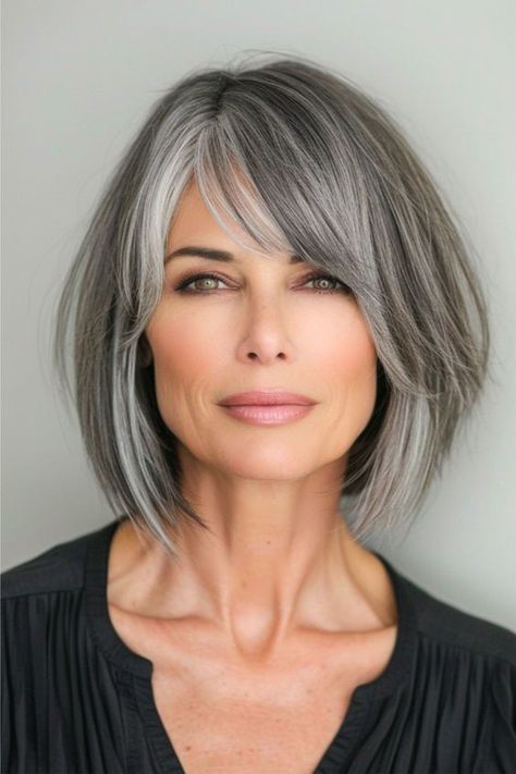 A smoky salt and pepper bob combines the edge of sharp angles with the softness of feathered layers. The color seamlessly transitions back and forth from black to gray, offering a modern twist on the classic bob. Click here to see more stunning bob hairstyles for women over 60. Medium Salt And Pepper Hairstyles, Medium Hair Bobs For Women, Grey Layered Bob Hairstyles, Narrow Face Haircuts, Short To Medium Bob Hairstyles, Bobs For Grey Hair Over 50, Shoulder Length Bob Grey Hair, Texturized Bob Medium, Hair Color Ideas For Women 60