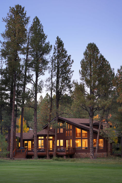 a twilight image taken of a cabin luxury home in Flagstaff Arizona, The home with brown siding is located deep in the trees beyond a grass field Interior Design Commercial, Composition Techniques, Flagstaff Arizona, Architectural Interior, Luxury Cabin, Flagstaff, The Cabin, Interior Design Firm, Phoenix Arizona