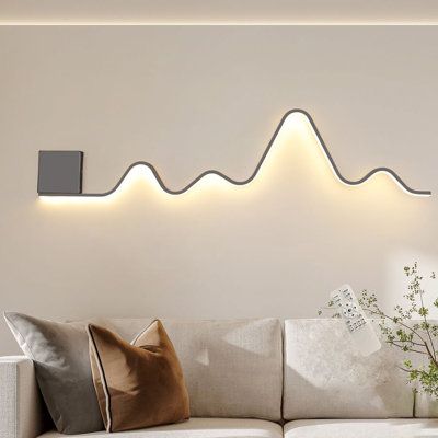 The wall sconce lighting fixture designed in a unique wavy and linear structure shape, add more fashion elements to your house, blends with most types of home decoration style. This modern wall sconces have a memory function. When you turn it on, it will maintain the lighting mode you turned off last time. And its light color and brightness can be adjusted. | Wrought Studio™ Heidamos 1 - Light 43.3" Aluminum LED Flush Mounted Sconce Metal in Black / White | 7.08 H x 43.3 W in | Wayfair Entryway Wall Lights, Modern Ambient Lighting, Wall Lights Behind Sofa, Wall Art Lighting Ideas, Picture Ledge With Lights, Dining Room Wall Lighting, Behind Couch Lighting, Creative Bedroom Lighting, Lights Behind Couch