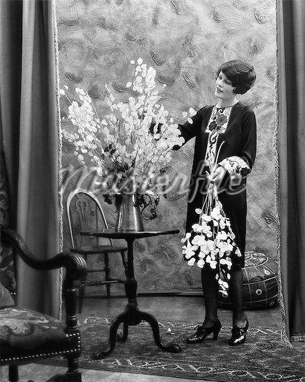 1920s WOMAN ARRANGING FLOWERS IN ALUMINUM PITCHER Stock Photos 1920s Woman, 1920s Women, Arranging Flowers, Cloud Canvas, Rainbow Canvas, Flower Vase Arrangements, Cow Canvas, Vintage Rentals, The Masterpiece