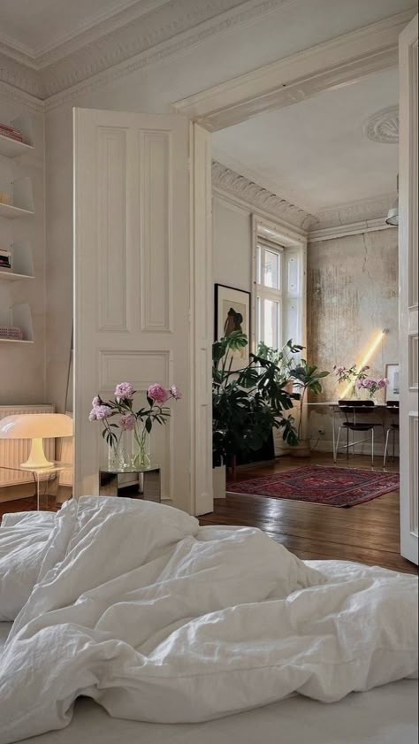 an unmade bed sitting in a bedroom next to a white door and window with flowers on it