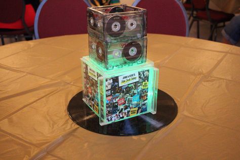 This is the centerpiece from our party, featuring a 12" record base, five cd cases with inserts customized for our party, topped with eight cassettes for that old school feel. Balloons with weights can be inserted, along with LED tea lights (as shown here). 2000s Party Centerpieces, Cd Centerpiece Ideas, 2000s Theme Party, Hip Hop Birthday Party, Country Music Playlist, 50th Birthday Themes, Stall Decorations, 2000s Theme, Throwback Party