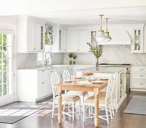 Kitchen features white bamboo chairs at a light brown French dining table with turned legs next to a white center island with light gray countertop lit by green and white pendants and white cabinets with light gray top. Light Gray Countertops, Roman Shades Kitchen, White Pendants, Light For Kitchen Island, Light Fixtures Ceiling, Bamboo Chairs, Gold Pendant Light, French Dining Tables, Brown French