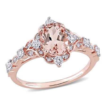 This intricately designed Miabella Vintage Halo Ring is the epitome of beauty and grace. Crafted in lustrous rose gold, this sophisticated ring features an oval-cut prong-set morganite gemstone (8x6mm) encased in a beautiful halo design created by eight round-cut prong-set white sapphire gemstones (2.25x2.25mm)(2x2mm) and 16 round-cut pave-set diamonds (G-H, I1-I2). Enhanced with a polished finish, this classic ring is perfect for a quick glam fix. This classic and sparkling piece is indeed a ti Verragio Engagement Rings Rose Gold, Rose Gold Halo Ring, Vintage Halo Ring, Rose Gold Oval Engagement Ring, Verragio Engagement Rings, Pretty Engagement Rings, Vintage Halo, Rose Gold Halo, Cute Engagement Rings