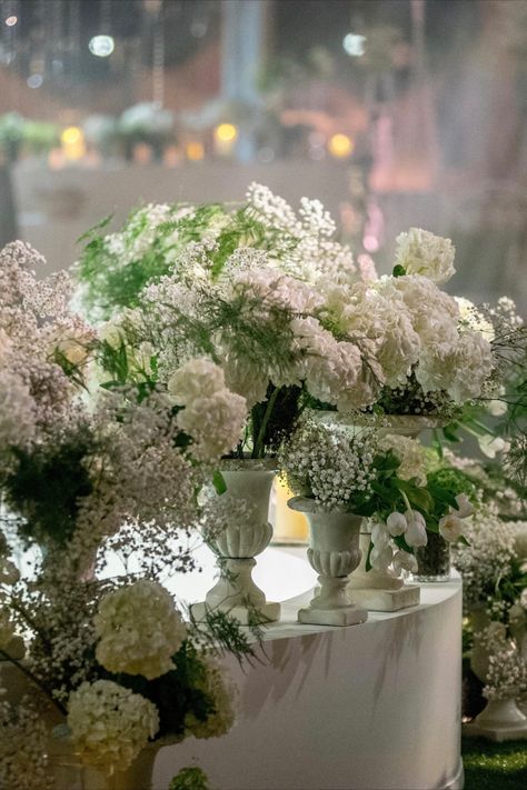 Sophisticated white floral arrangements with hydrangeas and baby's breath in classic urns, adding timeless elegance. Urn Floral Arrangements, Arrangements With Hydrangeas, White Floral Centerpieces, White Urn, White Floral Arrangements, Garden Indoor, French Garden, Baby's Breath, Floral Centerpieces