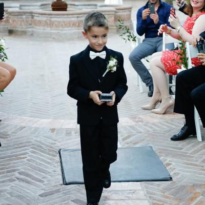 Ring bearer walks down the aisle in cute all black tux and precious cargo | One Fine Day Photography | villasiena.cc