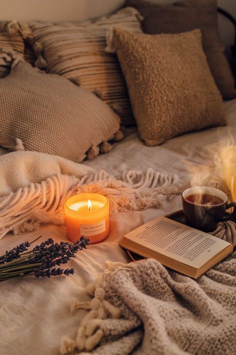 A lit candle, a book, and a cup of tea on a bed with a cozy blanket. Perfect for a relaxing evening. Book And Tea, Chunky Knit Blanket, Cozy Night, Book Candle, Cozy Reading, Cozy Living Rooms, Cup Of Tea, Knitted Blankets, Soft Lighting