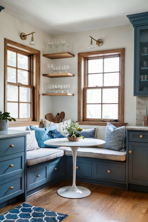 A corner kitchen nook featuring blue cabinets and bench seating with a white round table and wooden floating shelves Built In Seating Kitchen, Kitchen Banquet Seating, Kitchen Seating Nook, Built In Kitchen Nook, Updated Kitchen Ideas, Kitchen Corner Booth, Corner Bench Kitchen Table, Window Seats Ideas, Castle Interior Design