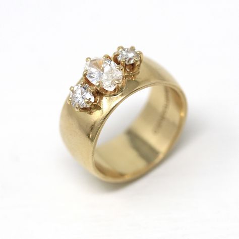 Show-stopping Retro era 14k yellow gold genuine three stone diamond ring! This chunky gold ring showcases a sparkling 0.72 carat oval faceted center diamond that is flanked by two round diamonds on the sides. The gems are secured in prong settings, and are centered in the middle of the 9.6 mm wide band. Would make an incredible alternative style engagement ring, and would look phenomenal stacked with other rings or paired with a wedding band. Stunning diamond ring, circa 1970s! The ring includes Chunky Round Engagement Ring, Unique Chunky Wedding Rings, Wide Gold Band Engagement Rings, 1980s Engagement Ring, 70s Engagement Ring, Chunky Gold Engagement Ring, Chunky Engagement Rings, Grandma Ring, Chunky Wedding Band