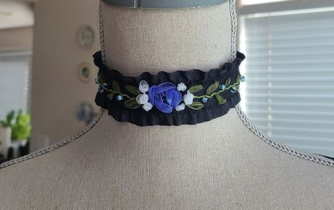 "This lovely choker features beautiful black ruffled ribbon with blue, white and green beaded floral embroidery. It is inspired by the gorgeous choker designs of the past. The choker is 12 1/4\" around with a nickel free lobster claw clasp and a 2\" extender chain. An elegant choker reminiscent of the 18th and 19th centuries. Comes in a lovely gift box with ribbon. Hand Embroidered. In the Eighteenth and Nineteenth centuries, chokers were very fashionable. Some were made of pearls, lace or ribbo Jewelry 18th Century, White Flower Choker, Embroidery Choker, Red Crystal Jewelry, Dark Blue Jewelry, 18th Century Jewelry, Art Deco Drop Earrings, Hand Embroidered Jewelry, Elegant Choker