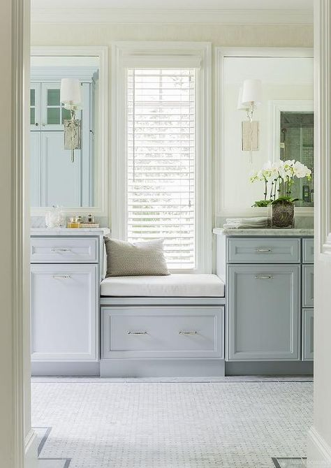 Gorgeous bathroom features a a built-in window seat with drawer flanked by separate vanities fitted with blue gray cabinets adorned with nickel hardware topped with gray and white marble under white beveled vanity mirror illuminated by Hudson Valley Lighting Glenford Sconces alongside marble basket weave tiled floor accented with gray border tiles. Blue Bathrooms Designs, Built In Window Seat, Vanity Seat, Guest Bathroom Remodel, Bathroom Remodel Pictures, Bathroom Window, Small Remodel, Transitional Bathroom, Gorgeous Bathroom