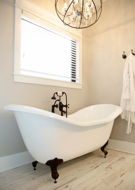 Vintage farmhouse style bathroom with a modern clawfoot tub and a rod iron decorative light overhanging. White wash floors for that classic farmhouse style. Tour the rest of this home by checking out our gallery of stylings by This New Old House Modern Clawfoot Tub, Rod Iron Decor, New Old House, Farmhouse Style Bathroom, White Washed Floors, Bathroom Lighting Design, Bathroom Chandelier, Best Kitchen Design, Rod Iron