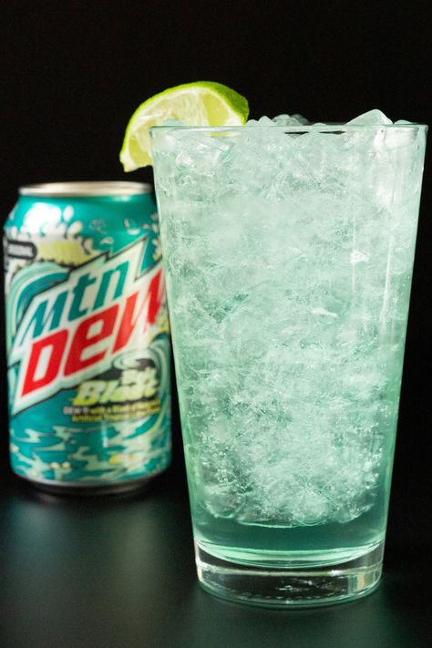 A pint glass filled with pebble ice and a turquoise colored cocktail. A can of Baja Blast is out of focus in the background. Baja Blast Margarita, Baja Blast Cocktail, Taco Bell Drinks, Mtn Dew Baja Blast, Mountain Dew Baja Blast, Iced Caramel Macchiato Recipe, Banana Dog Treat Recipe, Taco Bell Quesadilla, Homemade Crunchwrap