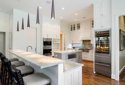 With light gray marble exterior and snow white wood fixtures, this kitchen island glimmers brightly under uniquely shaped accent lights. Kitchens With Two Islands, Narrow Kitchen Island, Massive Kitchen, Best Kitchen Designs, Kitchen Island Design, White Cabinetry, Luxury Kitchen Design, Spacious Kitchens, Red Kitchen