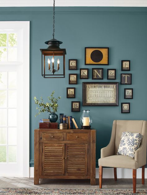 Looking for a farmhouse-style shade with a vintage twist? This medium-toned blue delivers, pairing beautifully with eclectic wall art and old-fashioned furniture. The paint color is also nicely picked up in accents like the rug, throw pillow, and even the display of old books!  Shown here: Pratt & Lambert Blue Shoal 314E  #colorofthemonth #bluestone #bluewallcolor #farmhousestyle #farmhousedecor #colortrends #paintcolortrends #homedecor #homeimprovement Blue Walls Living Room, Blue Painted Walls, Blue Wall Colors, Color Of The Month, Blue Accent Walls, Living Room Wall Color, Paint Your House, Room Wall Colors, Wall Colour