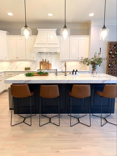 Kitchen with white cabinets, blue island, brass hardware, wood accents, and metal & leather barstools. Designed by L Reaves Interiors. #LRIdesign #LReavesInteriors #kitchen #blueisland #quartzcounter #barstools Navy Blue Island With Bar Stools, Kitchen Island Dark Blue, Kitchen With Dark Island And White Cabinets, Blue Accent Kitchen Island, White Kitchen Navy Blue Island Gold Hardware, Colored Kitchen Island With White Cabinets, White Kitchen With Dark Blue Island, White Cabinet With Navy Blue Island, Accent Color On Kitchen Island