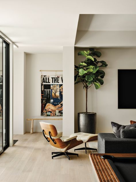 An Eames lounge chair and ottoman lend a midcentury modern touch to the lower-level family room. Greg Miller artwork purchased via JoAnne Artman Gallery hangs on a back wall. Eames Lounge Chair Living Room, Eames Chair Living Room, Morrison Interiors, Chaise Long, Lounge Chair And Ottoman, Lounge Chairs Living Room, Luxurious Home, Eames Chairs, Architecture Home