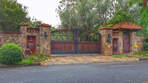 Spanish inspired driveway gate and pedestrian door beautifully constructed in Rancho Santa Fe, CA. Gated Home Exterior, Mexican Gates Hacienda Style, Hacienda Entrance Gates, Mediterranean Gate Entrance, Spanish Driveway Gate, Spanish Style Driveway Gate, Spanish Fences And Gates, Gated Entrance Landscaping, Wooden Gate Designs Driveways