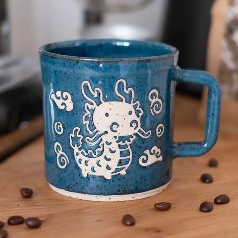 A little dragon appears! After many months of research, design, and making, the first ceramic pieces of my dragon collection will become available April 26. The majority of the work will be this 400 ml mug, along with a few other designs, and maybe even a few dragon plates too. With 3 weeks left, there's still a lot to do - but I can't keep putting off the release! Besides, I plan to continue adding to this collection for the entire year anyway :) Which means I also have the rest of the ye... Dragon Pottery Painting, Drawing On Pottery, Cup Designs Ideas, Ceramic Bowl Designs, Painting Ceramics Ideas, Mug Designs Painted, Dragon Pottery, Ceramic Plates Designs, Ceramic Dragon