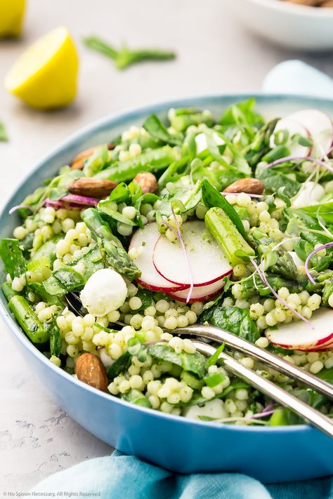 45 degree angle shot of Vegetable Couscous with Lemon Basil Pesto with serving spoons inserted into the bowl and a teal linen, bowl of almonds, lemon wedge and basil leaves blurred in the background. Mediterranean Salad Recipes, Pesto Couscous, Fresh Bowls, Vegetable Couscous Salad, Lemon Basil Pesto, Mediterranean Salad Recipe, Vegetable Couscous, Spring Salad Recipes, Salad With Lemon