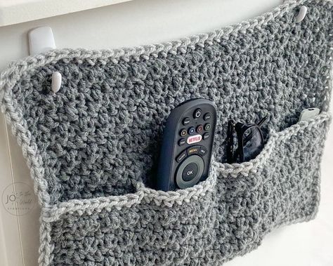 This quick and easy pattern for a crochet remote/glasses/phone holder will instantly de-clutter and organize your room. You can finally clear up much needed space on your side table and keep all your remotes, glasses, and phone nicely tucked away while your side table is beautifully clear. Looking for terrific crochet gift ideas? Make two and now you have gifts for him and her! This Remote Holder Crochet Pattern is super simple, perfect for beginners and works up really quickly. You can use ... Remote Organization, Remote Caddy, Crochet Organizer, Remote Control Holder, Crochet Christmas Gifts, Remote Holder, Crochet Abbreviations, Easy Crochet Baby, Easy Crochet Projects