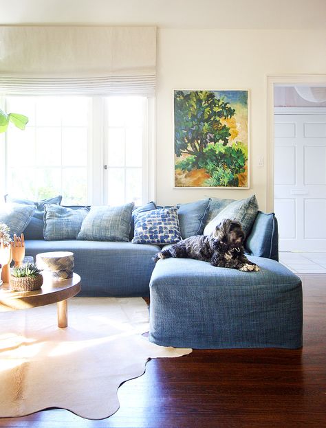 Blue L-shaped sofa in living room with small dog, forest art, and styled coffee table Relaxed Living Room Decor, Denim Sofa, Colorful Couch, Shaped Couch, Relaxing Living Room, Couch Ideas, Blue Couch, Family Room Furniture, Corner Couch