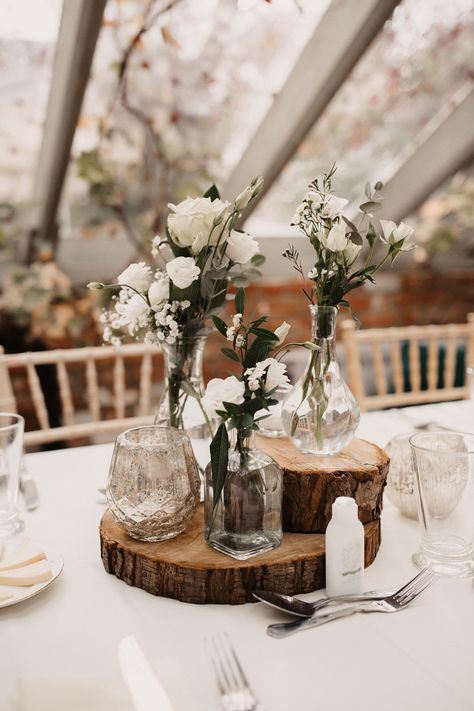 Rustic Wedding Table Centrepieces with White Flowers and Tree Slice Stands White And Wood Wedding Decor, Simple Rustic Table Setting Wedding, Wedding Small Table Decor, Small Rustic Wedding Decor, Tree On Table Wedding, Rustic Table Setting For Wedding, Centrepieces Round Table Wedding, Wedding Table Decorations Without Flower, Tree Slice Centerpiece Wedding