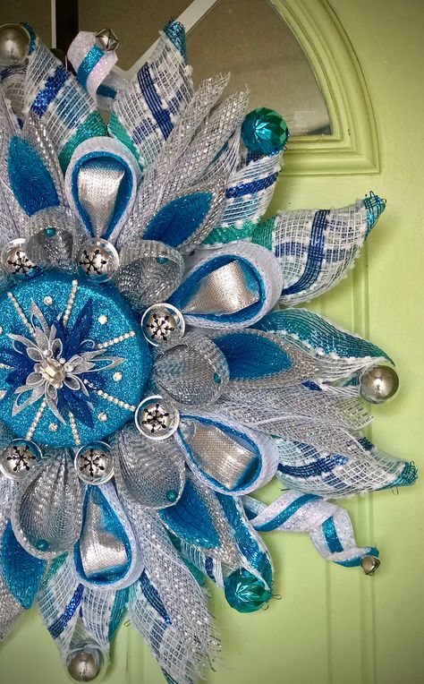 Knock-your-socks- off Christmas wreath in stunning, glittering blues, whites and silver. Various petal folds in blue stripes, silver and blues encompass a gorgeous center created from blue glitter foam & a handmade snowflake surrounded by rhinestone trim and a huge rhinestone center.  Large silver jingle bells nest inside the Lolly petals while small blue ornaments adorn the striped petals.  This is an amazingly beautiful wreath design that absolutely shines and shimmers and will DEFINITELY have Blue Mesh Christmas Wreath, Netting Wreath, Blue And White Christmas Decor, Blue And White Wreath, Christmas Snowflakes Wreath, Mesh Projects, Blue Ornaments, Diy Christmas Candy, Diy Floral Wreath