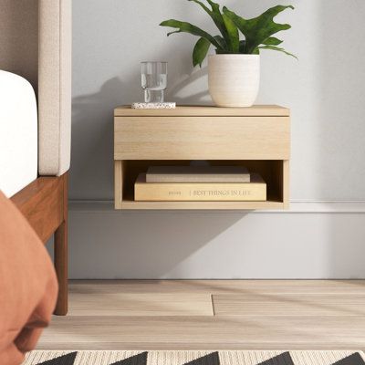 This floating nightstand mounts to the wall, saving you floor space in your bedroom with a sleek, modern style. It's crafted from engineered wood in a smooth, neutral finish that goes with a variety of color schemes. The wall-mounted design features a rectangular shape, and it measures about 9'' high, 16'' wide, and a little over 12'' deep. We love that despite its petite size, it includes both an open cubby shelf and a shallow, handleless drawer. Our favorite? Their floating construction means Modern Floating Nightstand, Floating Side Table, Floating Bedside Table, Bedroom Nightstand, Side Table Decor, Прикроватные Тумбочки, Modern Bedside Table, Modern Nightstand, Storage Drawer