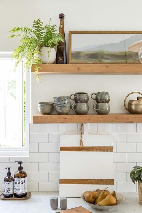 Stacked wood floating shelves are mounted over white subway kitchen wall tiles lined with light gray grout. Airbnb Kitchen, Kitchen Wall Design, White Subway Tile Kitchen, Pure Salt Interiors, Kitchen Floating Shelves, Shelves Decor, Subway Tile Backsplash Kitchen, Floating Shelves Kitchen, Pure Salt